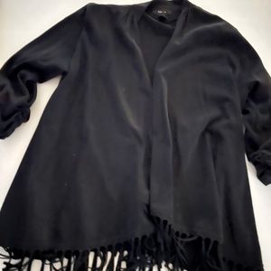 Large black cardigan with fringe around the bottom hem.